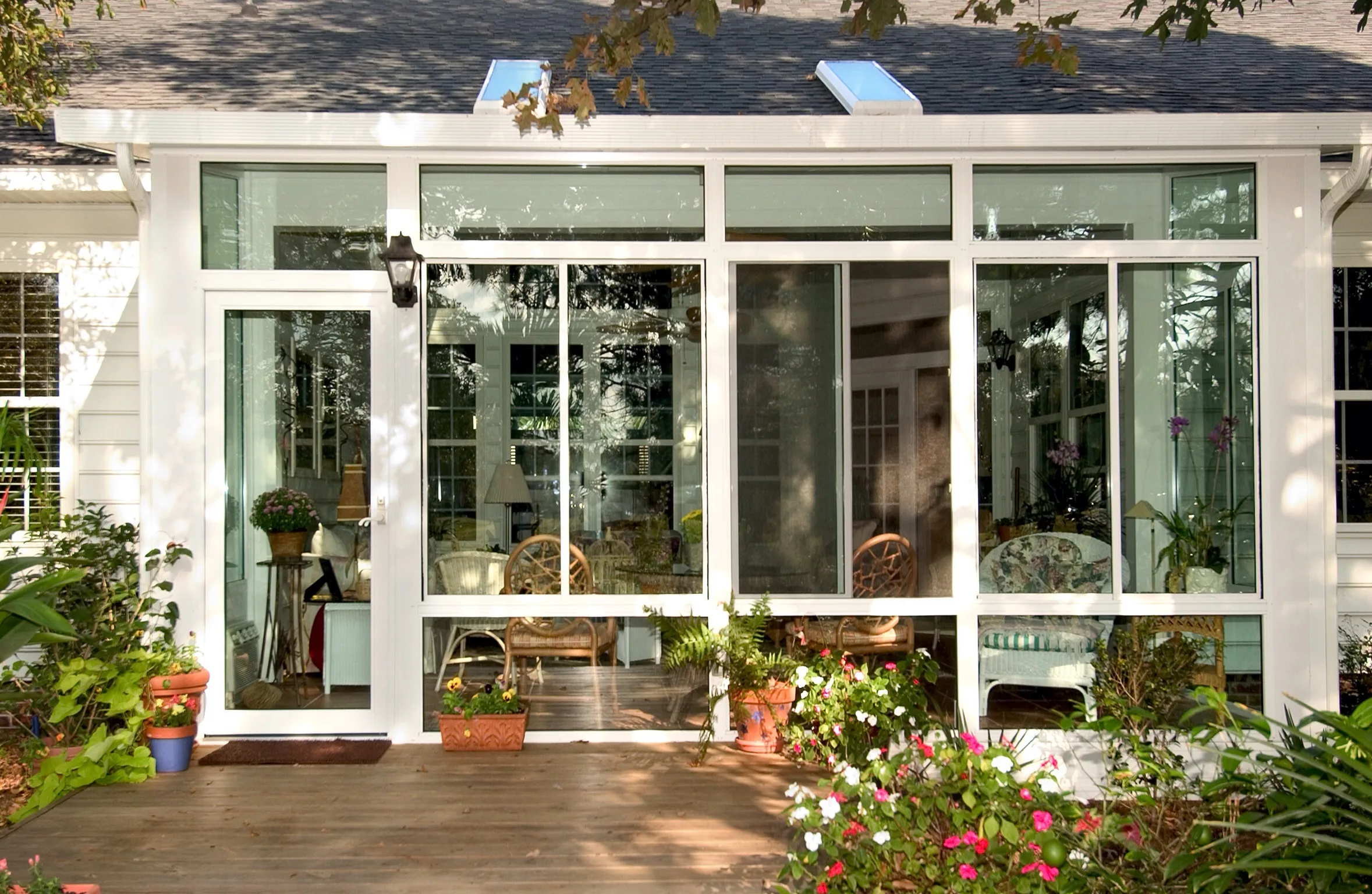 Exterior of a TEMO Studio-style sunroom addition with white aluminum framing and full-height glass walls